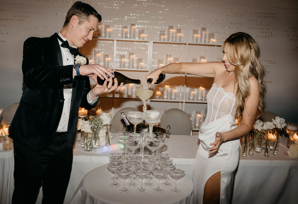 bride and groom pouring champagne into champagne tower